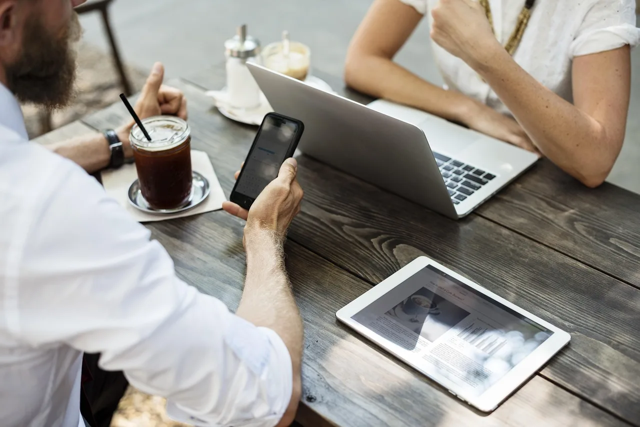 Business owner meeting a marketing agency over coffee with a laptop and phone on the table Business owner meeting a marketing agency over coffee with a laptop and phone on the table